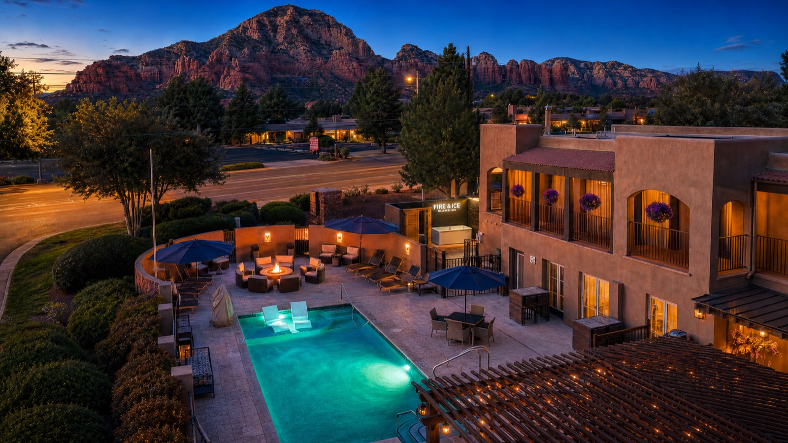 Aerial view of Arroyo Pinion at dusk: heated pool, fire pit, Fire & Ice wellness spa and guest rooms below the Sedona red rocks